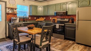 A kitchen with green cabinets, a wooden dining table, and a chandelier. - The Mountain Magnolia *Hot tub on private deck* (Inez)