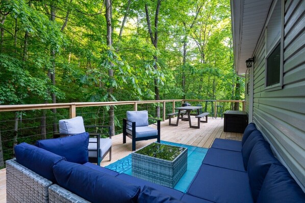A covered deck with outdoor furniture, a table, and a sofa.