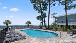 A swimming pool with lounge chairs and a view of the ocean. - Tranquil 2-bedroom condo with Wolf bay views (Orange Beach)