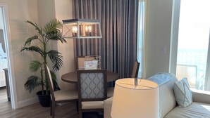 En moderne stue med en sofa, et bord med en lampe, et spiseområde med en stol og en potteplante.