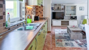 Una cocina moderna con un lavamanos grande, cestas de almacenamiento verdes y una estufa empotrada.
