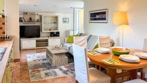 Una sala de estar moderna con televisor, sofá, mesa de comedor y zona de cocina.