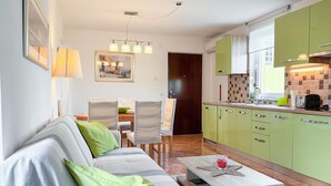 Un espacio habitable compacto con sofá, mesa de comedor, sillas y kitchenette.