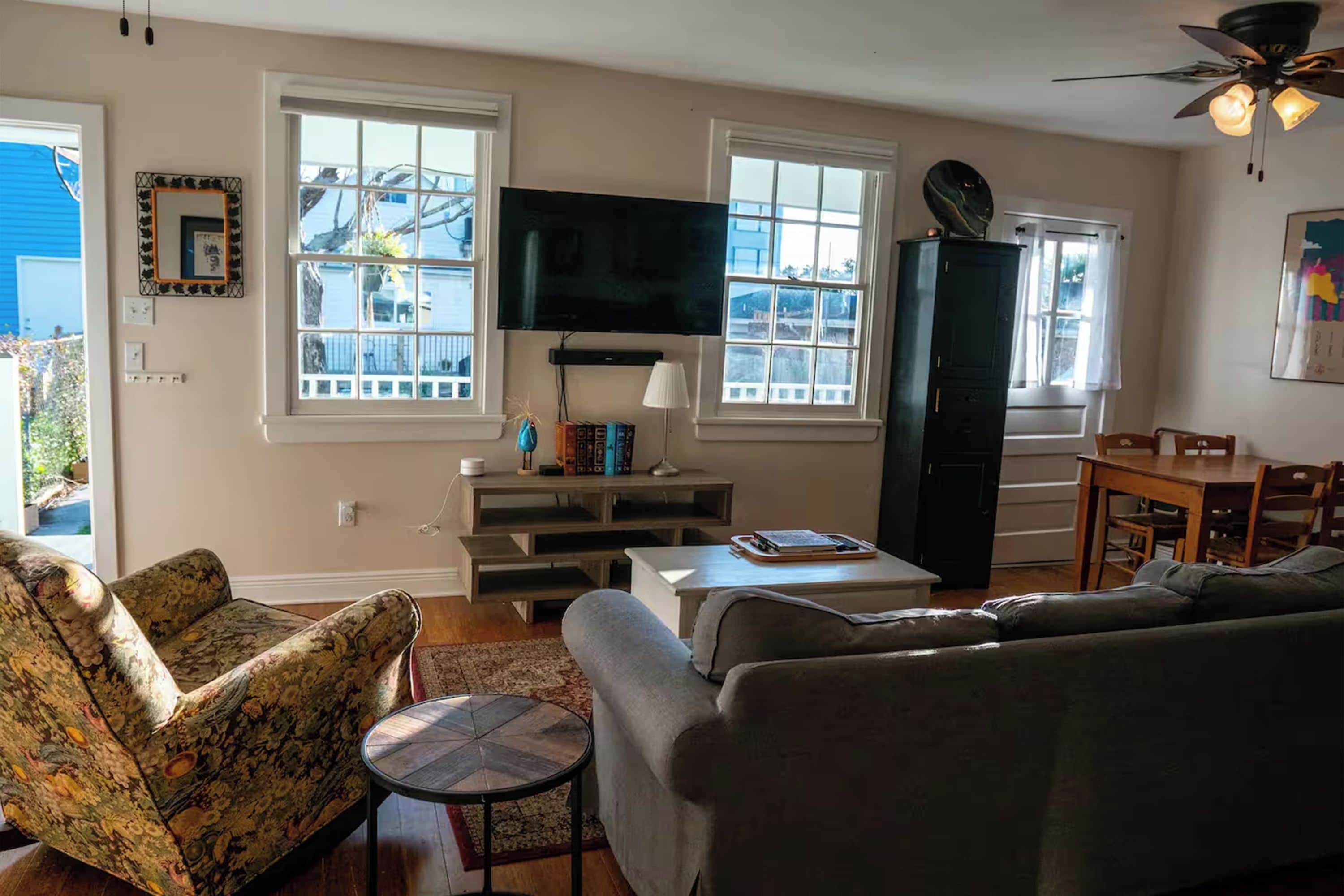 A living room with a sofa, armchair, TV, and a dining area with a table and chairs.