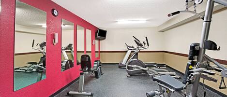 A gym with various exercise equipment, including treadmills and weight machines, and mirrors on the walls.