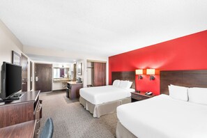 A hotel room with two beds, a desk, a TV, and a bathroom.