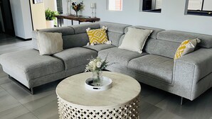 A modern living room with a grey sectional sofa, a round coffee table with a lattice base, and a small side table with a vase of flowers. - Two Williams Estate - Hunter Valley
4 Bedrooms, 2 Bathrooms, Pool Table (Kitchener)