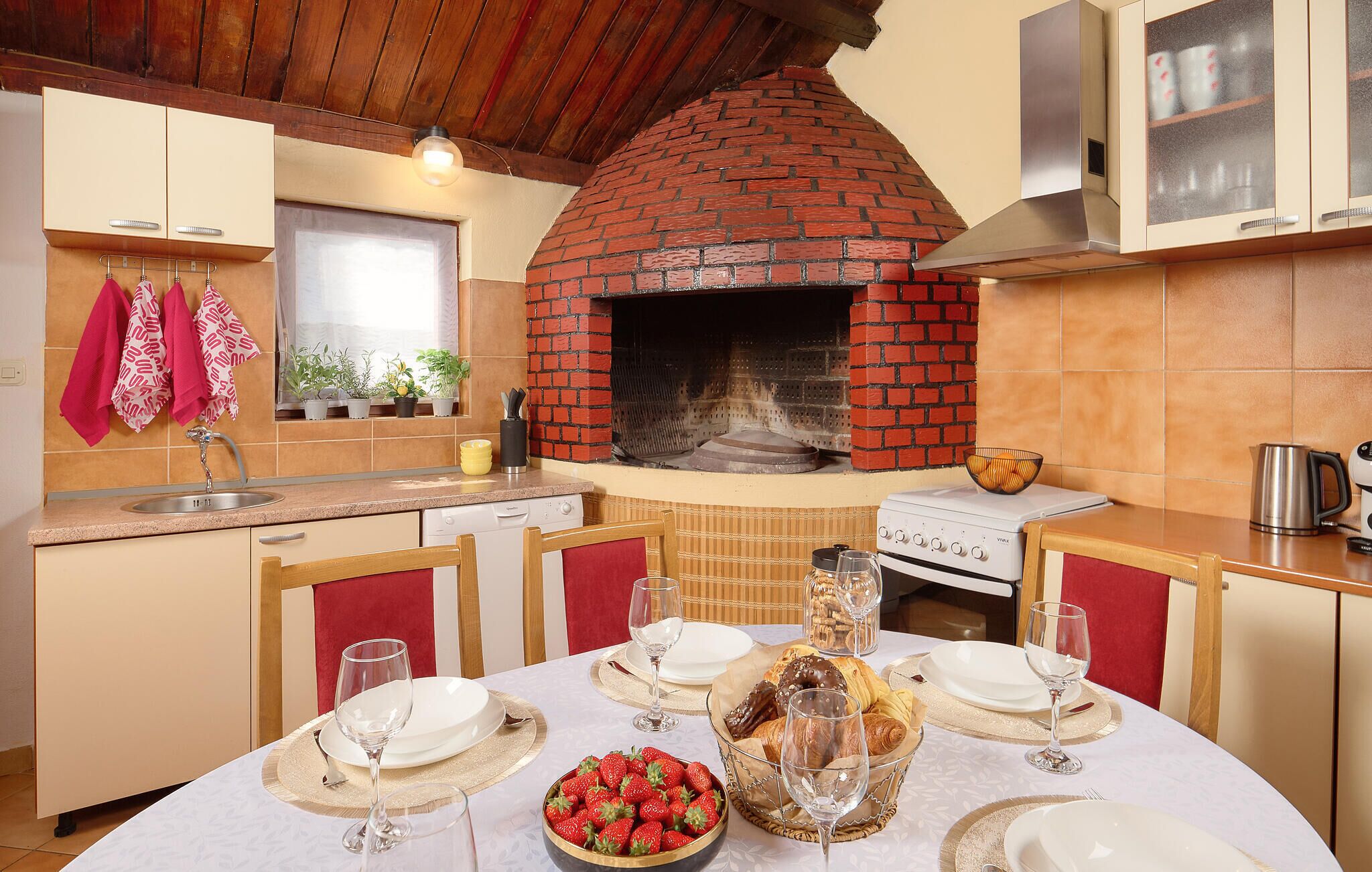 Une cuisine avec un four en briques, une table à manger dressée pour deux personnes et un évier.