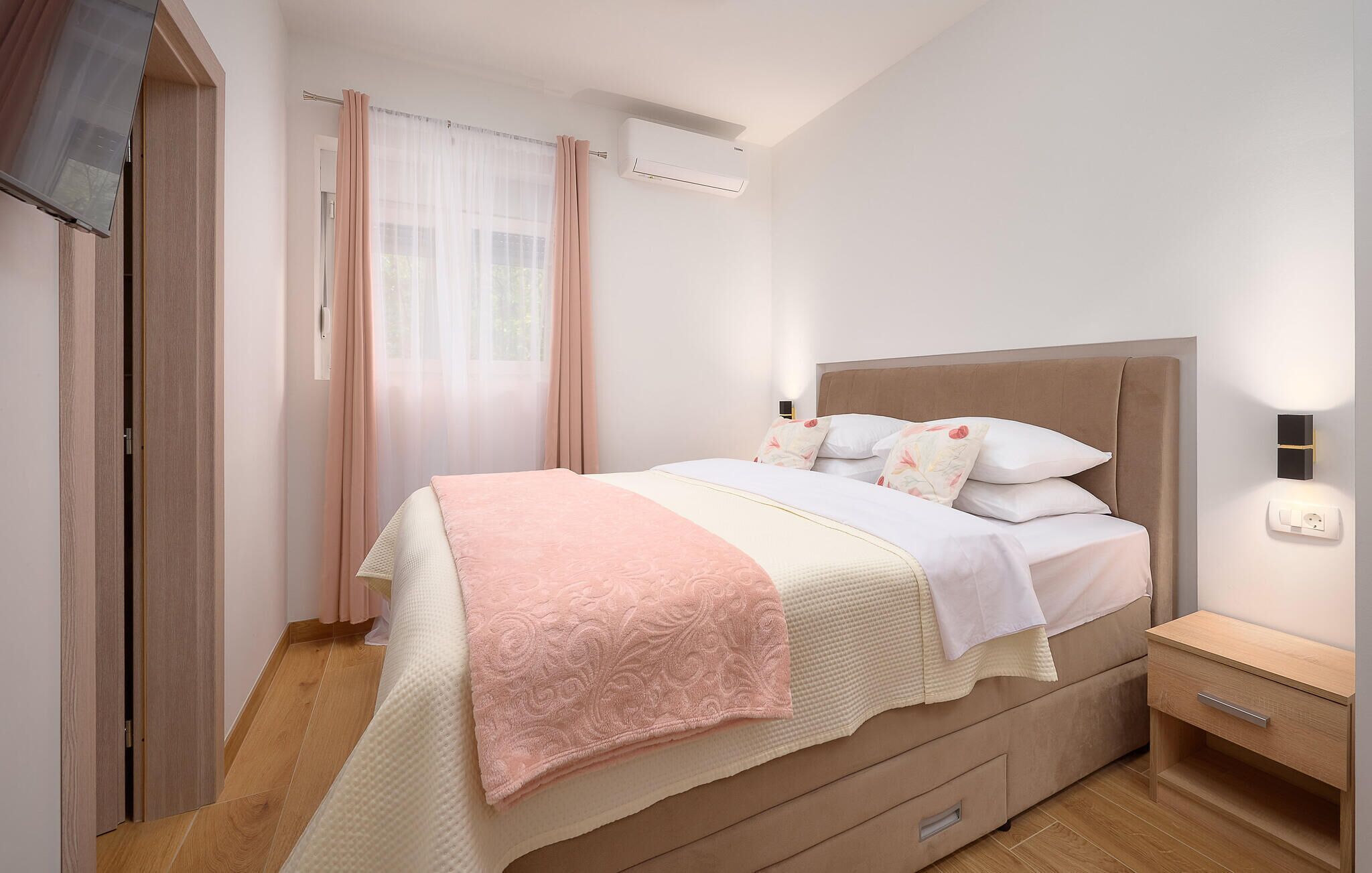 Un dormitorio con cama, mesita de noche y aire acondicionado de pared.