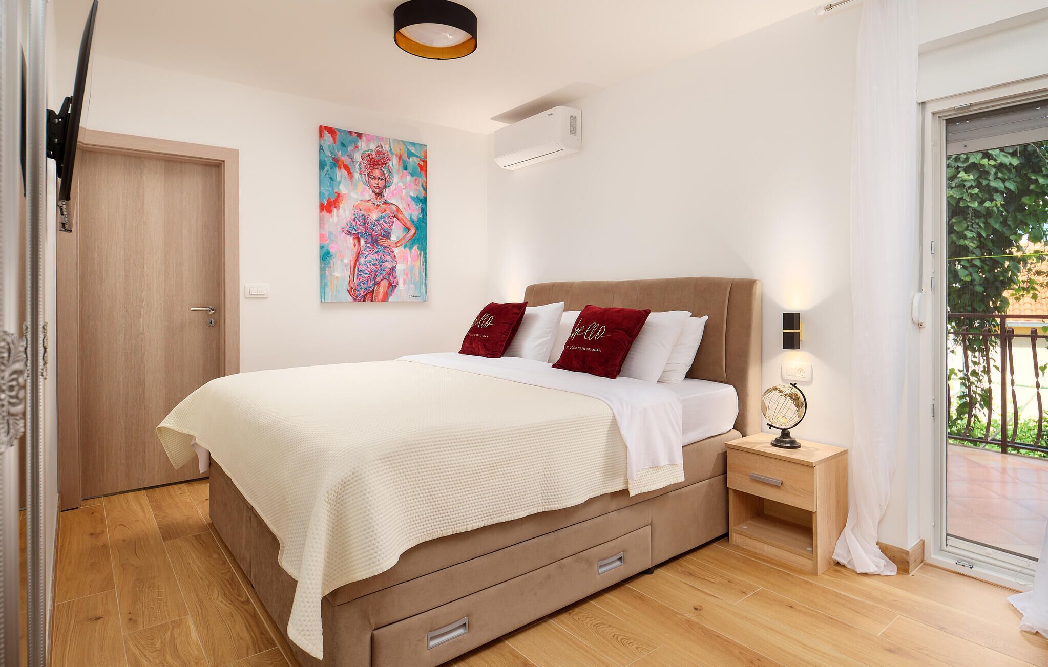 A bedroom with a bed, bedside table, and a painting on the wall.