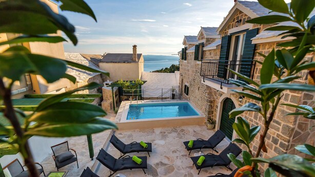 A pool area with lounge chairs and a view of the sea. - Amazing home in Baska Voda (Baska Voda)