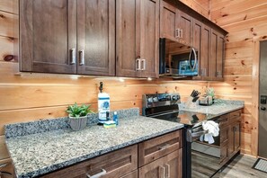 A modern kitchen with granite countertops, wooden cabinets, and stainless steel appliances. - A Spectacular View! *Hot Tub*Games*Pool*Dollywood! (Sevierville)