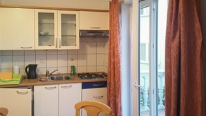 Une cuisine de taille réduite, avec des meubles blancs, un évier et une cuisinière.