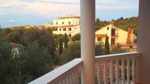 Un balcon doté d’une balustrade blanche, donnant sur un quartier résidentiel avec des maisons et des arbres.