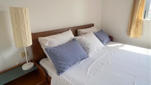 Un lit bien fait, avec des oreillers blancs et bleus, une tête de lit en bois et une lampe de chevet.