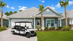 Ein zweistöckiges Haus mit Garage, Golfwagen und Palmen.