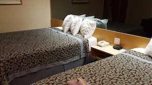 Ett hotellrum med två sängar, ett nattduksbord med en telefon och en resväska på golvet.