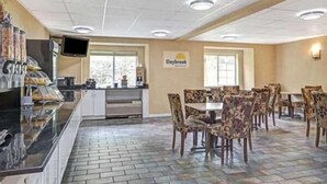 En matsal på Daybreak-hotellet med en buffé, sittplatser och ett kök i bakgrunden.