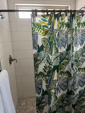 A bathroom with a shower curtain featuring a tropical leaf pattern. - Tropical Heaven - Unit 1600 - Island Dunes Condos (Port Aransas)