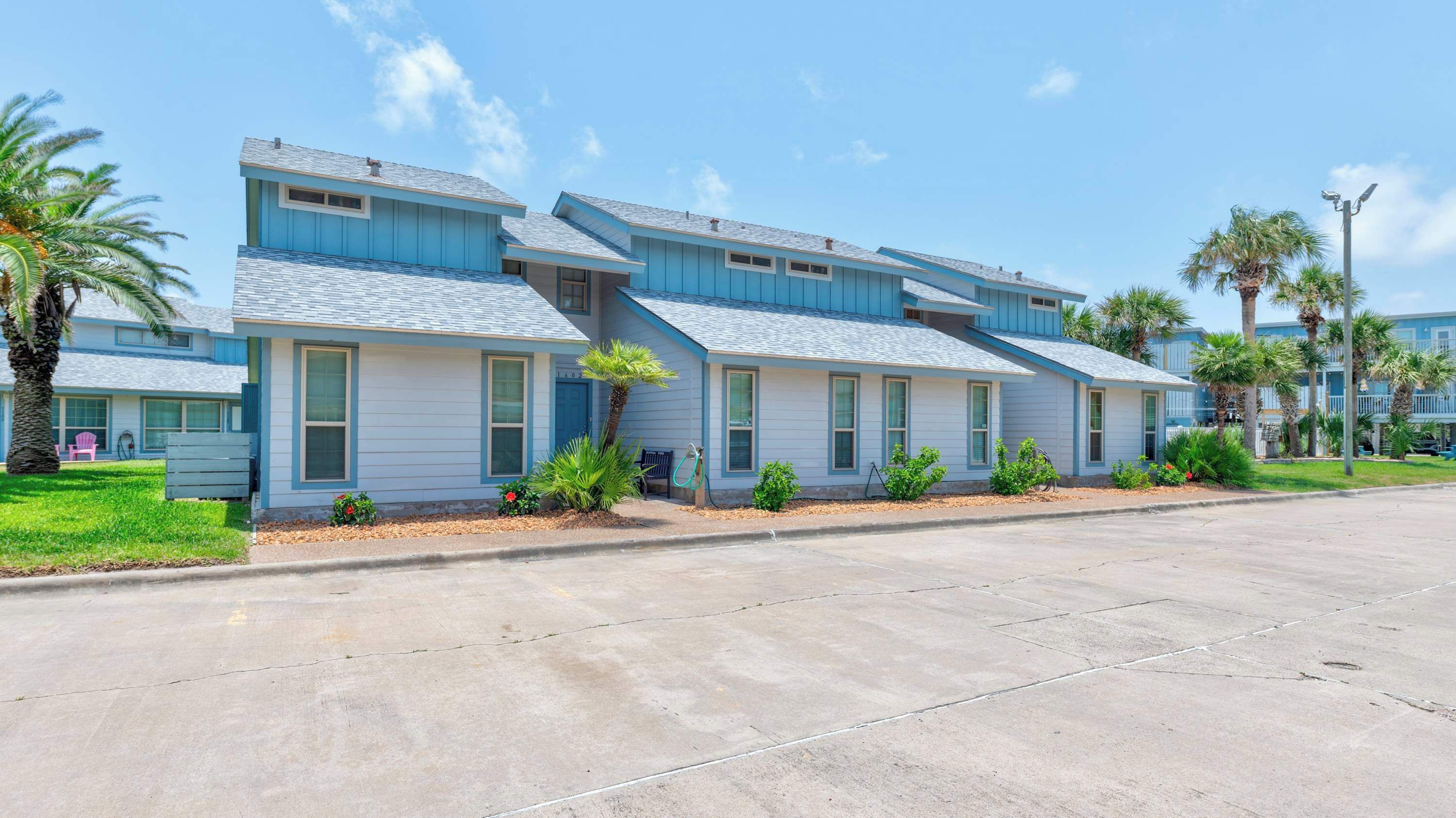A row of blue buildings with a flat roof and a small porch area.