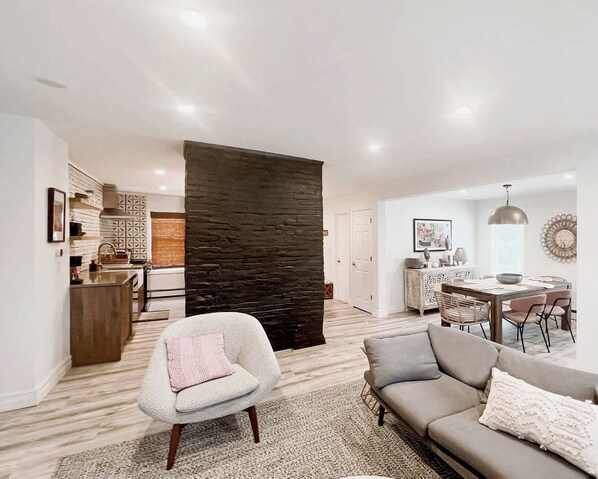 A modern living room with a sofa, armchair, and dining area.