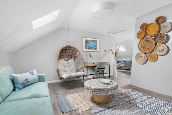 A modern loft bedroom with a hanging chair, a desk, and a round coffee table. - Downtown Warren Top Floor Loft 3BR: Spa | Walkable (Warren)