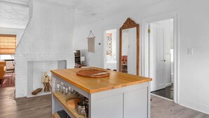 Uma cozinha com bancada de madeira, armários brancos e luminária pendente.