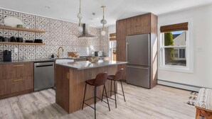 Eine moderne Küche mit Kochinsel, Barhocker, Kühlschrank und einem Fenster mit Blick.