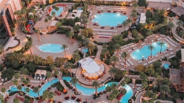 Ein Luftbild eines Resorts mit mehreren Schwimmbecken, Palmen und Liegebereichen.