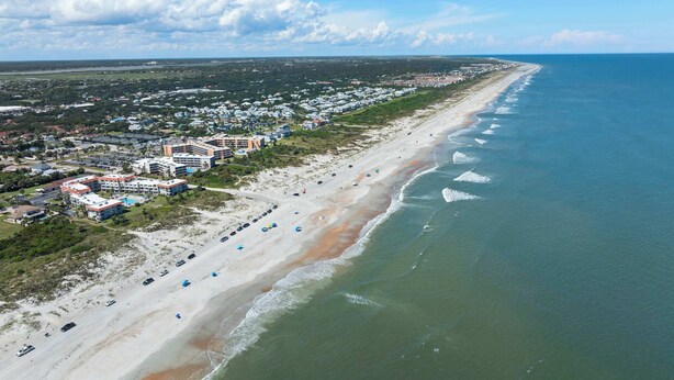 An aerial view of a coastal area with a beach, a row of hotels, and a clear sky. - Beachfront Getaway in St. Augustine (St. Augustine)