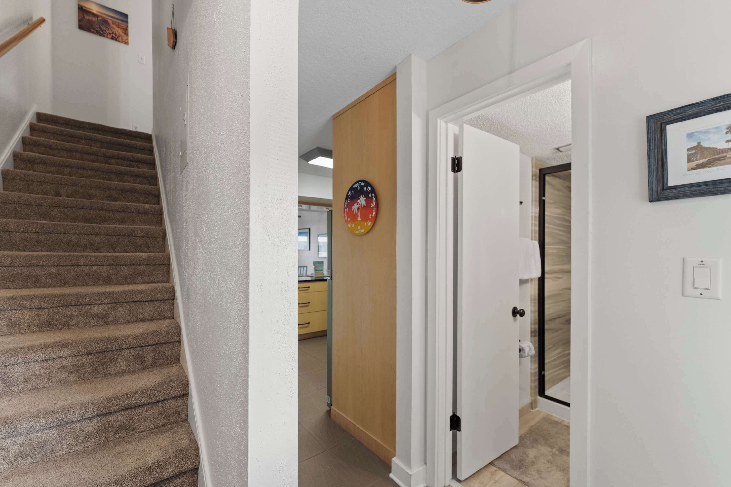 Eine Treppe führt zu einer Zwischenebene mit einer Holztür und einer Uhr an der Wand.