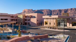 A modern hotel with a covered outdoor area, a parking lot, and a mountainous backdrop. - Spacious newly built 2-bedroom condo with AC in charming Moab (Moab)