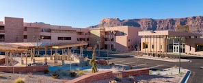 A modern hotel with a covered outdoor area, a parking lot, and a mountainous backdrop. - Spacious newly built 2-bedroom condo with AC in charming Moab (Moab)