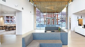 A modern hotel lobby with a reception desk, seating area, and large windows offering views of the outdoor area. - Spacious newly built 2-bedroom condo with AC in charming Moab (Moab)