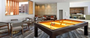 A modern lounge area with a pool table, comfortable seating, and a view of the cityscape through large windows. - Spacious newly built 2-bedroom condo with AC in charming Moab (Moab)