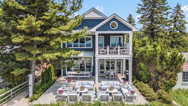 Une maison à deux étages dotée d’un balcon, d’un espace extérieur aménagé pour s’asseoir et offrant une vue sur les arbres environnants.