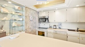 Una cucina moderna con mobili bianchi, forno a microonde, piano cottura e lavastoviglie.