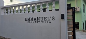 Un mur blanc sur lequel on peut lire l’inscription « VILLA RURALE D’EMMANUEL ».