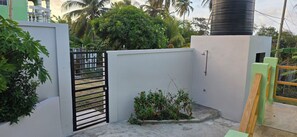 A gated courtyard with a concrete floor, a small flower bed, and a metal gate.