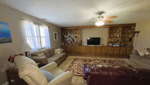 A living room with a sofa, armchair, and a television on a wooden cabinet.