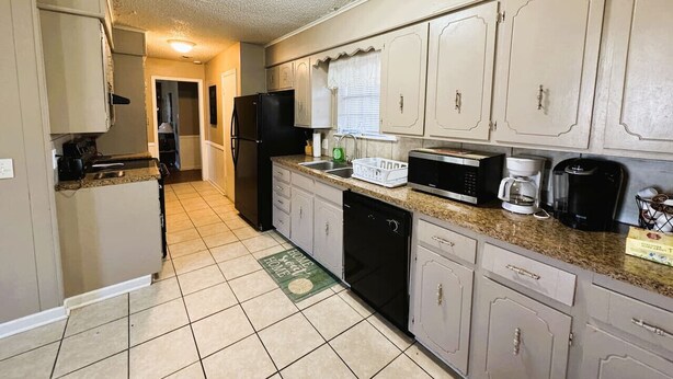 A kitchen with a refrigerator, microwave, coffee maker, and dishwasher.