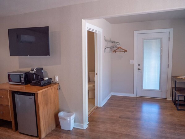 Un espacio habitable compacto con kitchenette, televisor de pantalla plana, microondas y refrigerador.