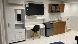 Eine kompakte Küche mit eingebautem Herd, einem kleinen Kühlschrank und einem Fernseher, der über der Arbeitsfläche angebracht ist.