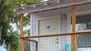 A single-story house with a wooden deck, a covered porch, and a door marked with the number 74. - Kerrville Standalone Cabin near Downtown & River (Kerrville)