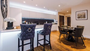 Una cocina moderna con una isla central, taburetes de bar y una mesa de comedor con sillas.