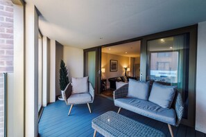 Ein Balkon mit Korbmöbeln, einem kleinen Tisch und einem Blumentopf.