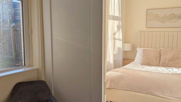Um quarto com uma cama, uma cadeira e uma janela.