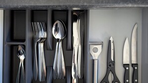 Uma gaveta de cozinha com utensílios e talheres.