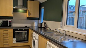 Uma cozinha compacta com armários de madeira, forno embutido, micro-ondas, máquina de lavar e lava-louças.