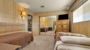 Habitación de hotel con dos camas, cabecera de madera, televisor de pantalla plana y armario.